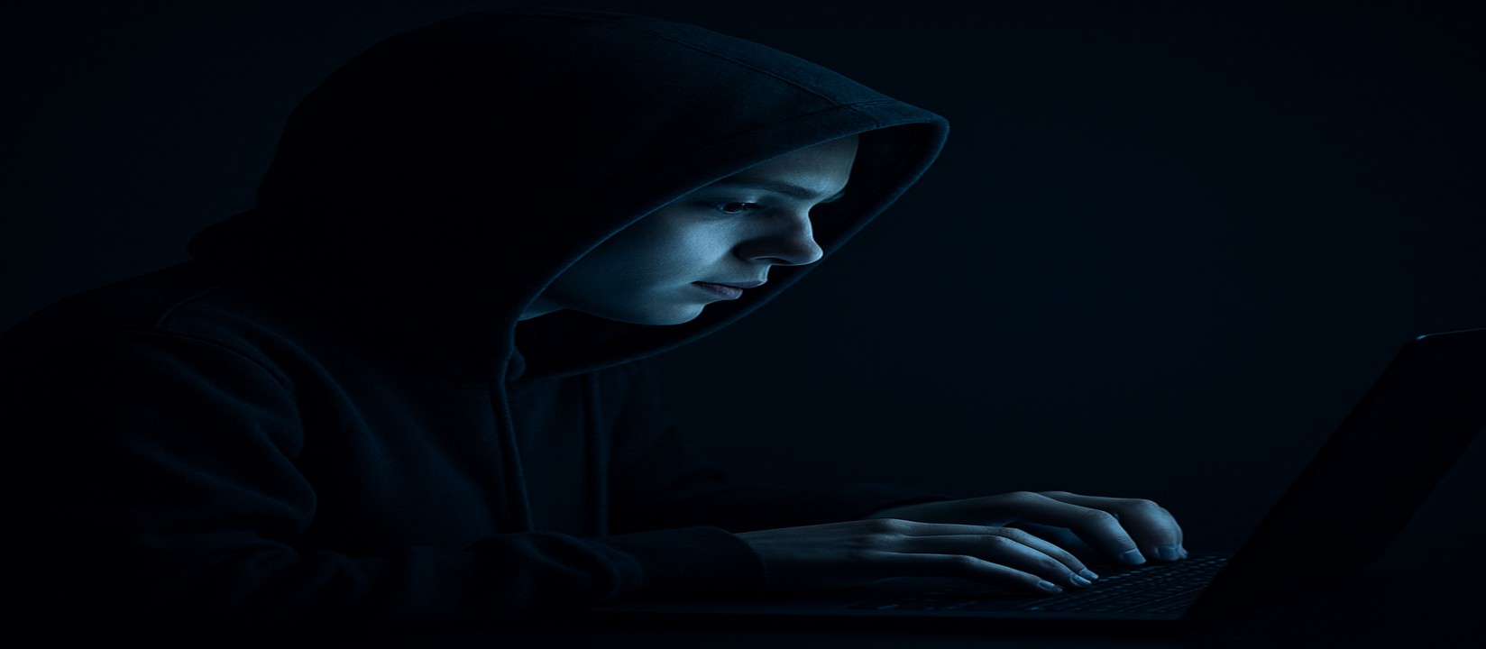 একজন ব্যক্তি অন্ধকারে ল্যাপটপে বসে একাগ্র দৃষ্টিতে jetbuzz ওয়েবসাইটে অনলাইন গেম খেলছেন